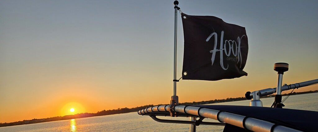 Sunset over water with a flag on a boat railing, featuring the word 'Hook'