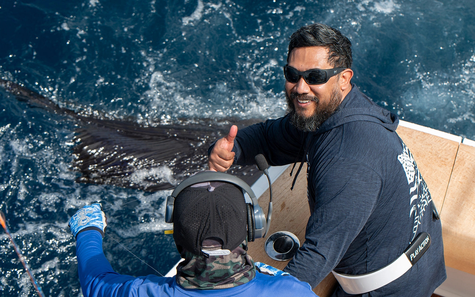 Angler wearing hook optics best sunglasses catching a sail fish in costa rica