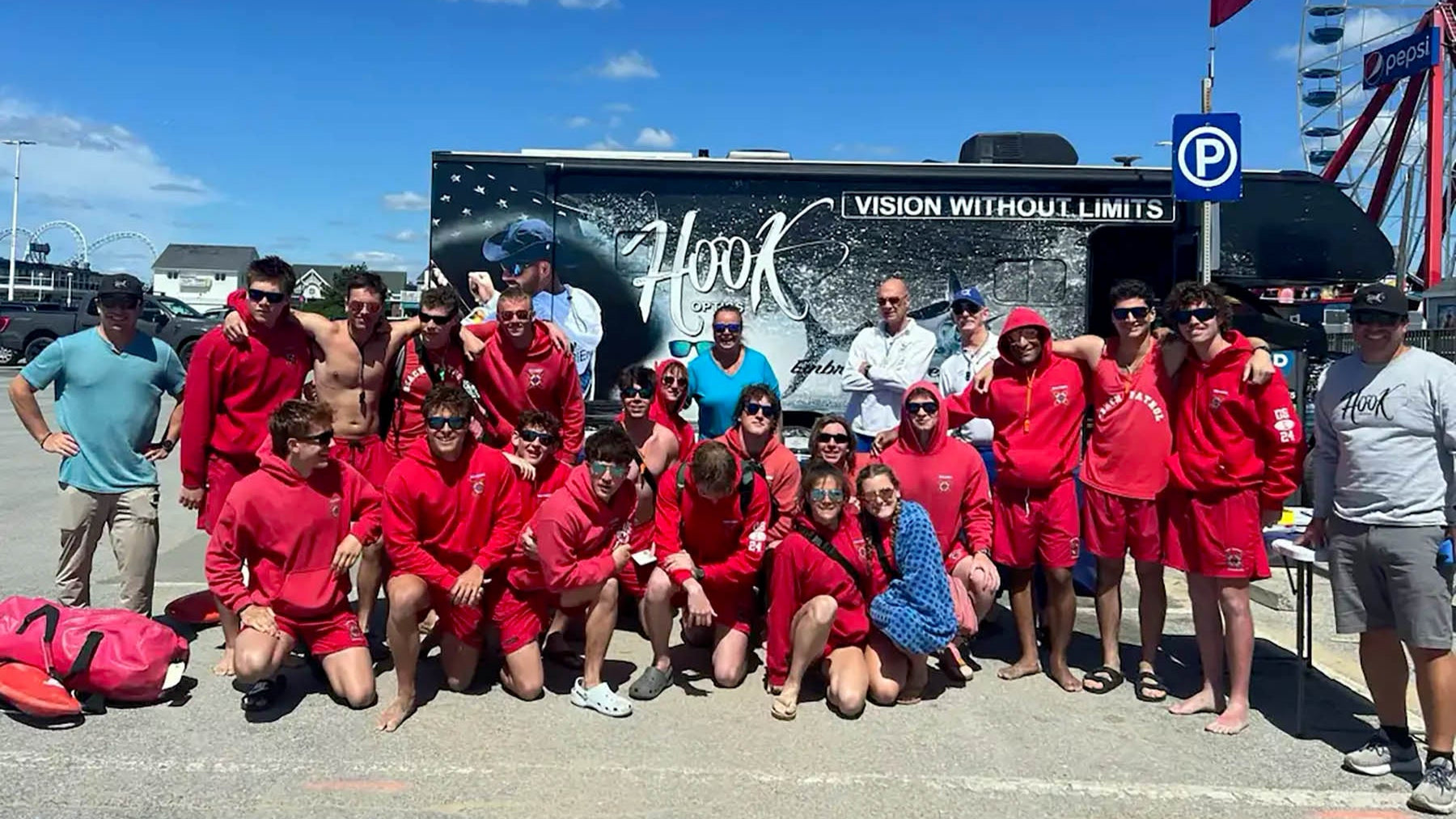 Ocean City Beach Patrol wearing Hook Optics posing in front of a large truck with 'Hook Vision Without Limits' on a sunny day.