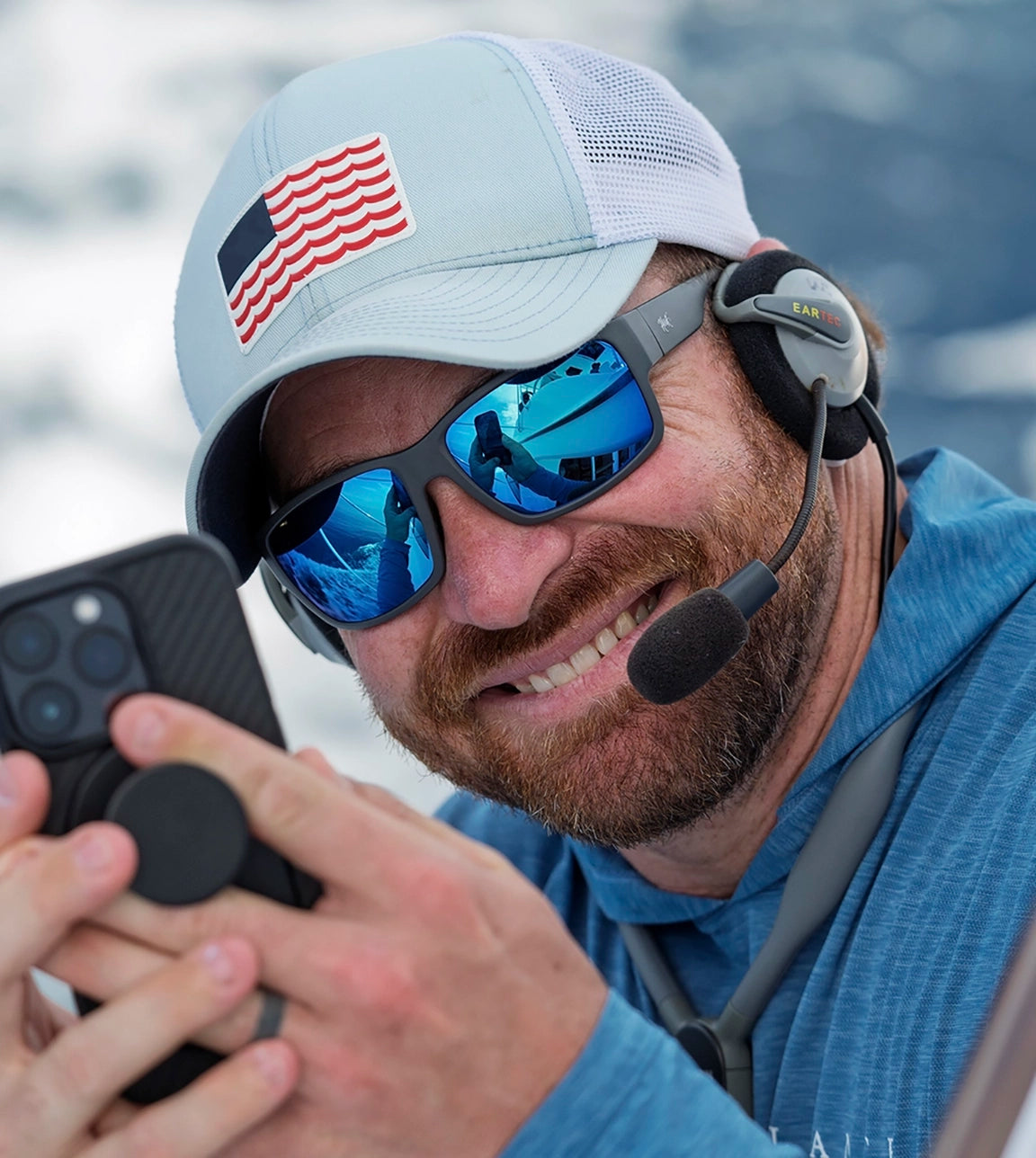 Angler smiling holding cell phone and wearing hook optics