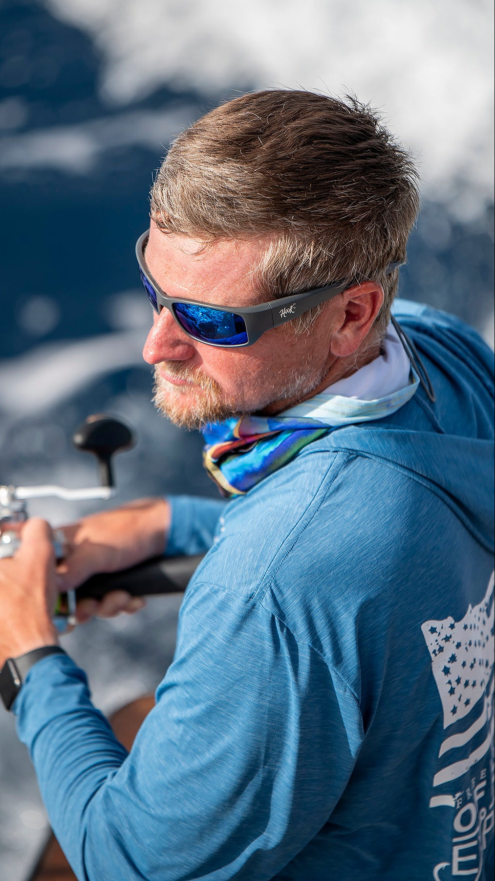 Man wearing hook optics sunglasses and a blue shirt on a boat with water in the background. fishing in Costa Rica