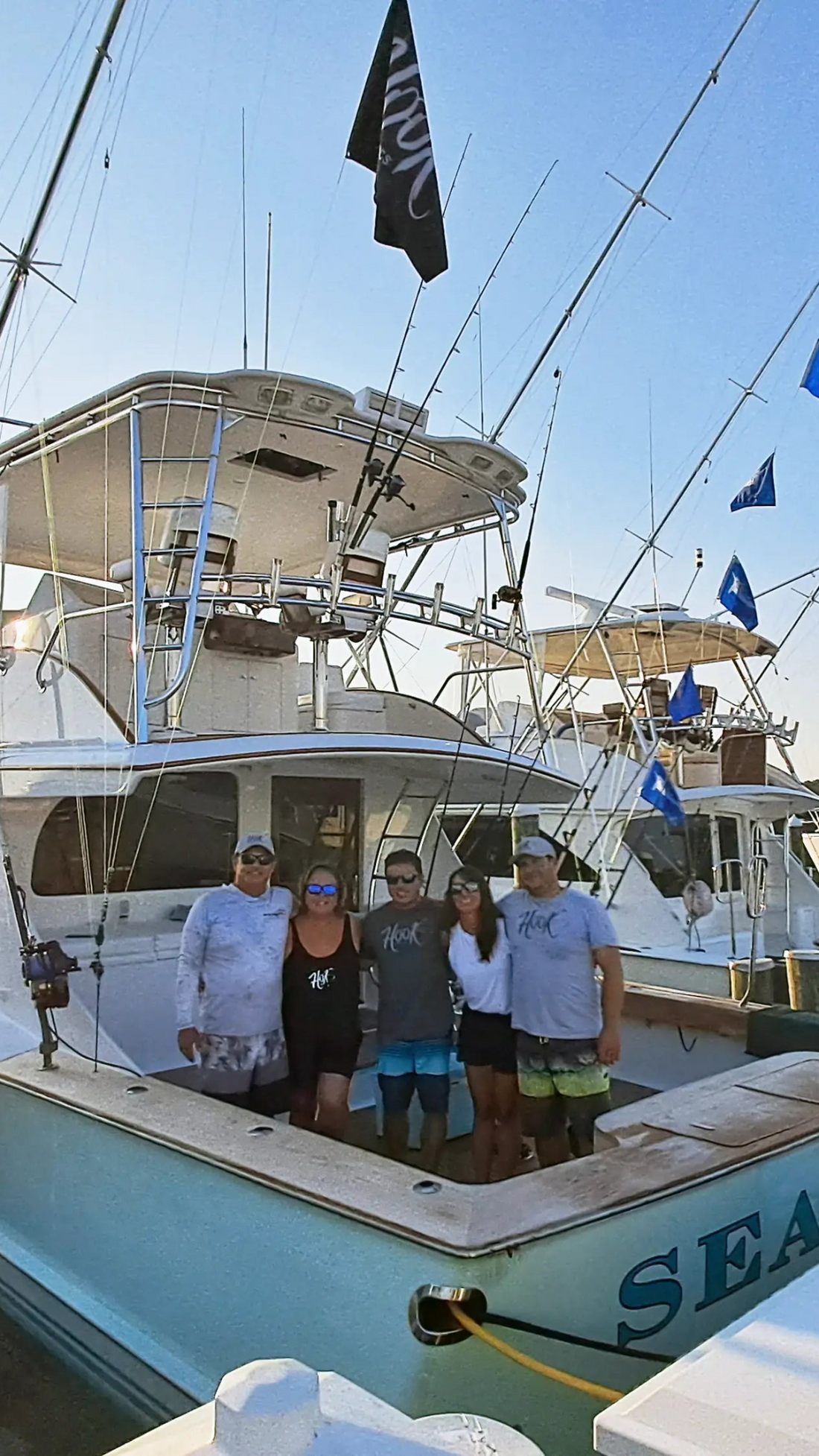 Group of people standing on a boat with clear blue sky. Hook Optics family photo