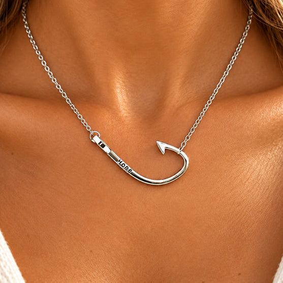 A silver necklace with a hook-shaped pendant engraved with 'I LOVE YOU' is shown on a model's neck.