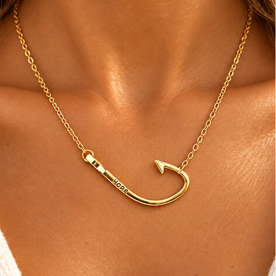 A gold chain necklace with a hook-shaped pendant engraved with the word 'HOD' (likely 'HODAY'), worn on a model's neck.