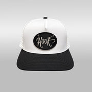 A black and white trucker hat with a white front panel, black brim, and a black oval patch on the front featuring the word 'Hook' in white script.