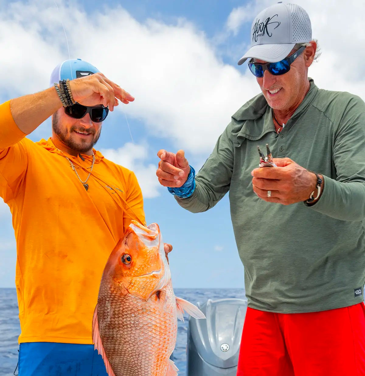 Two captins from the show into the blue on a boat holding a large fish with a clear sky in the background wearing hook optics sunglasses