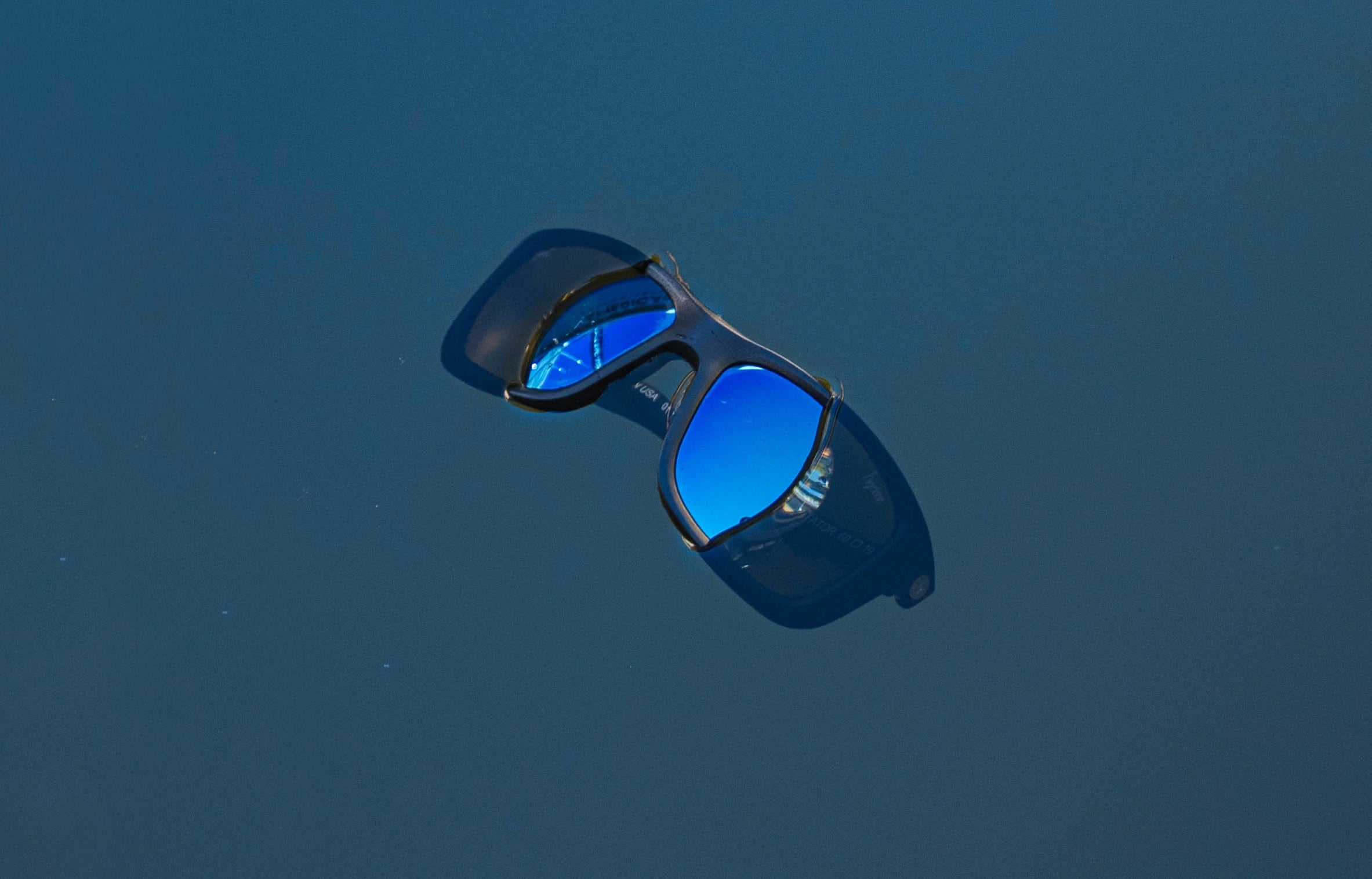 Blue reflective sunglasses floating in water, Sunglasses that float